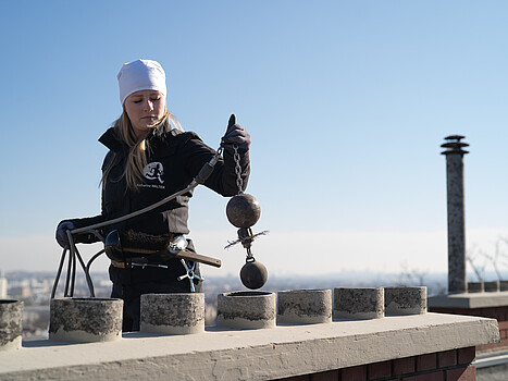 Female chimney sweep working on a roof
