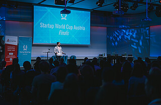 Startup World Cup Austria 2024 A man on a stage pitching at a startup competition