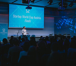 A man on a stage pitching at a startup competition