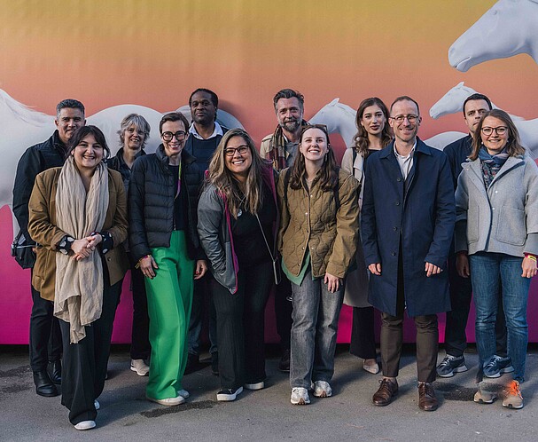 Group of people posing for a photo in front of a pink and orange background